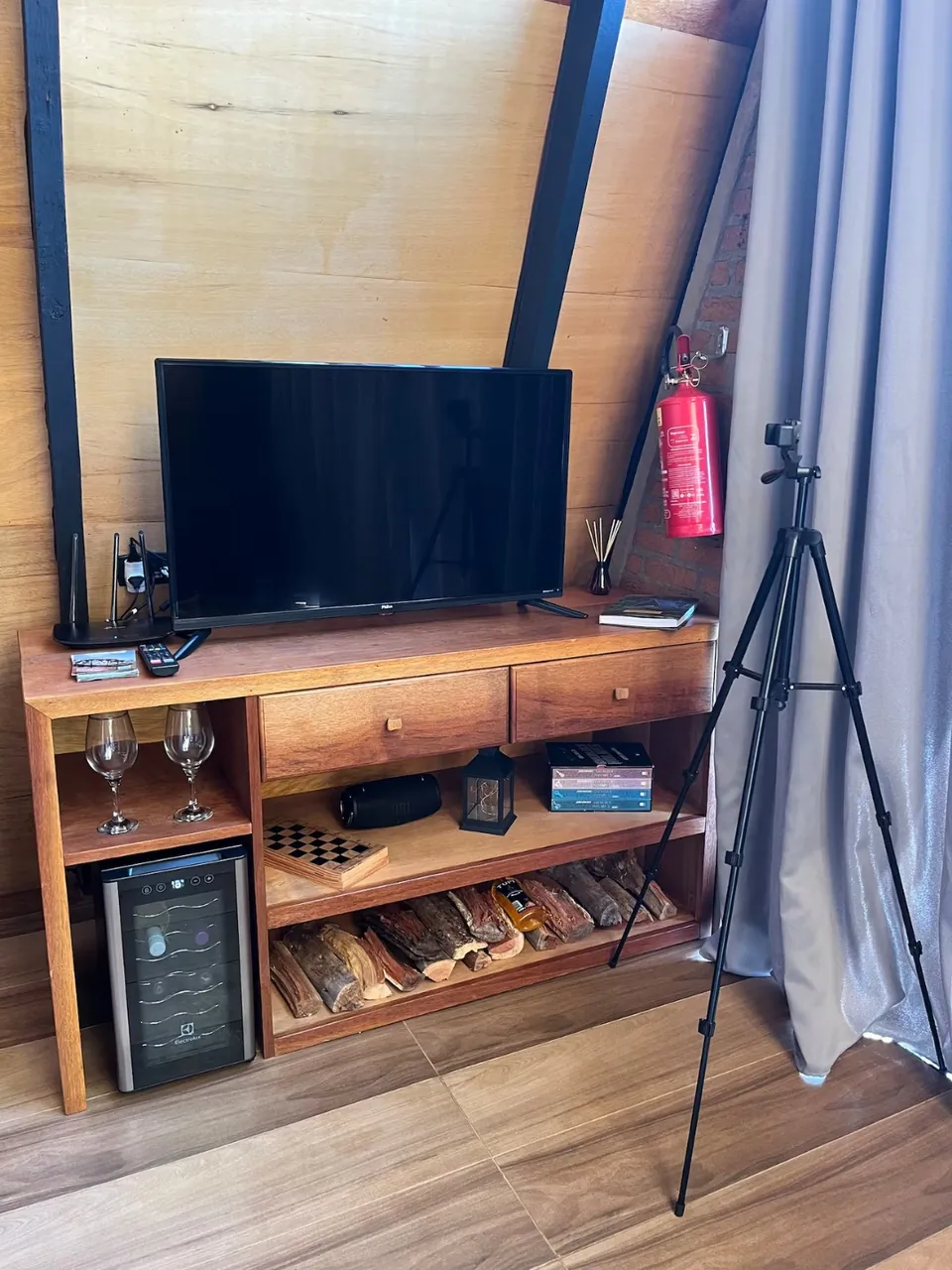 Móvel de madeira com televisão e adega no interior da Cabana Das Pedras.