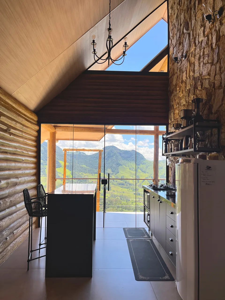 Cozinha da Araucárias com bancada, geladeira e porta de vidro para a varanda com vista da serra.