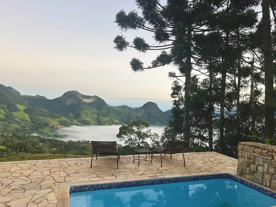 Piscina da Araucárias com cadeiras de frente para as montanhas e a névoa no vale.