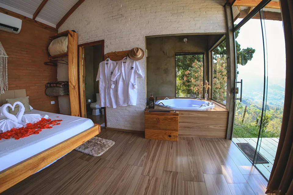 Quarto da Belvedere com cama decorada com pétalas e banheira de hidromassagem junto à porta de vidro.