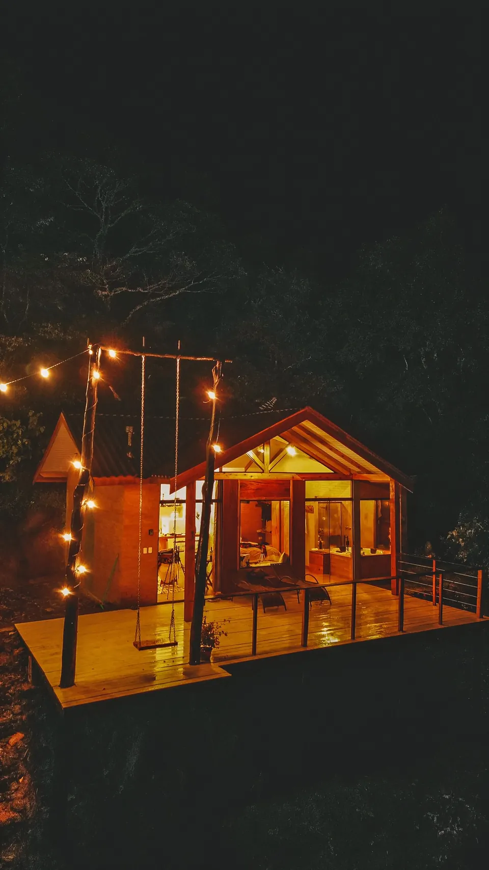 Belvedere à noite, com o deck e o balanço iluminados por um varal de luzes.