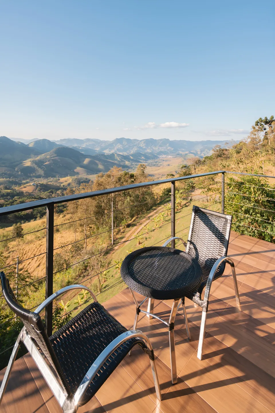 Mesa e duas cadeiras na varanda da Das Pedras, de frente para as montanhas.