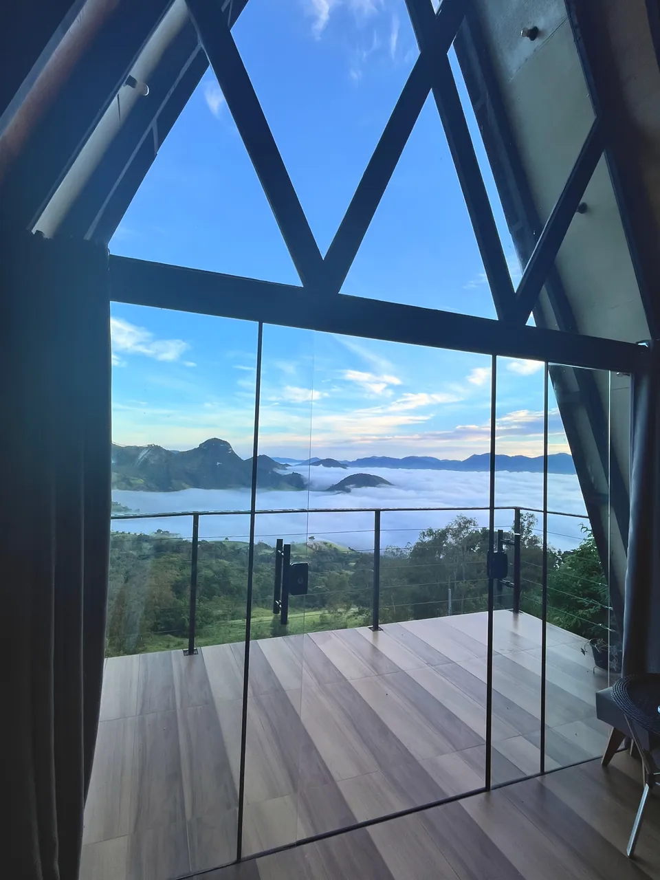 Vista da Das Pedras pela parede de vidro, com o vale coberto de névoa ao amanhecer.