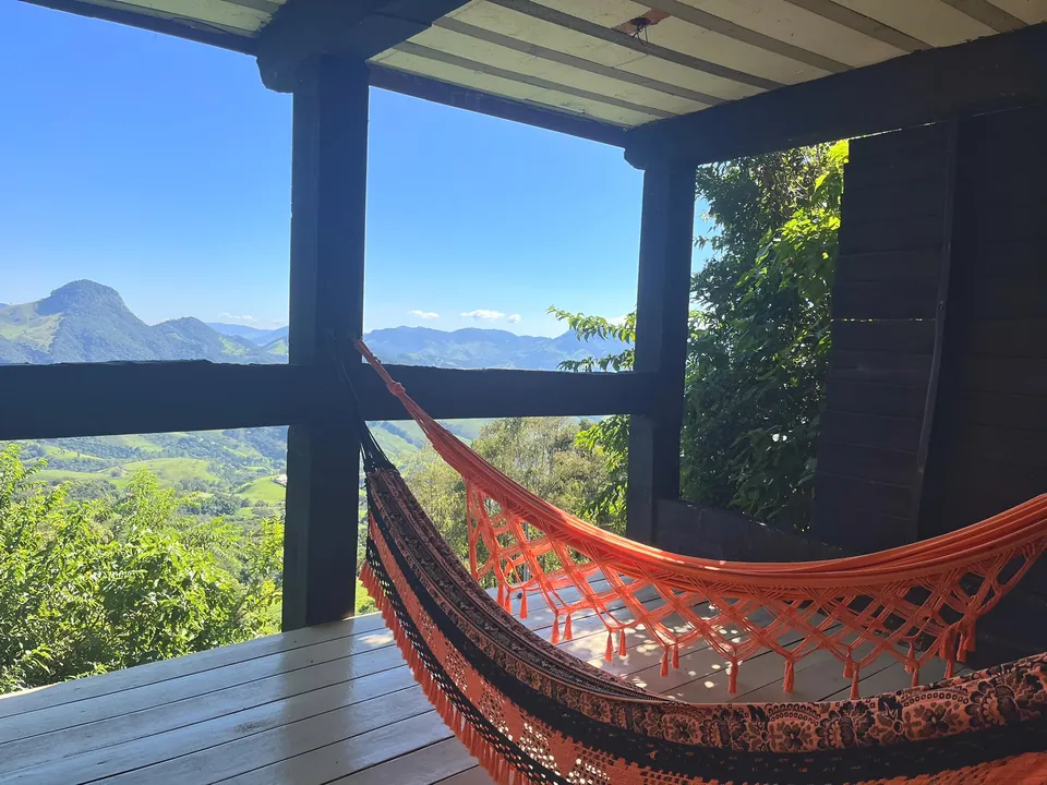 Rede laranja na varanda coberta, com as montanhas ao fundo.
