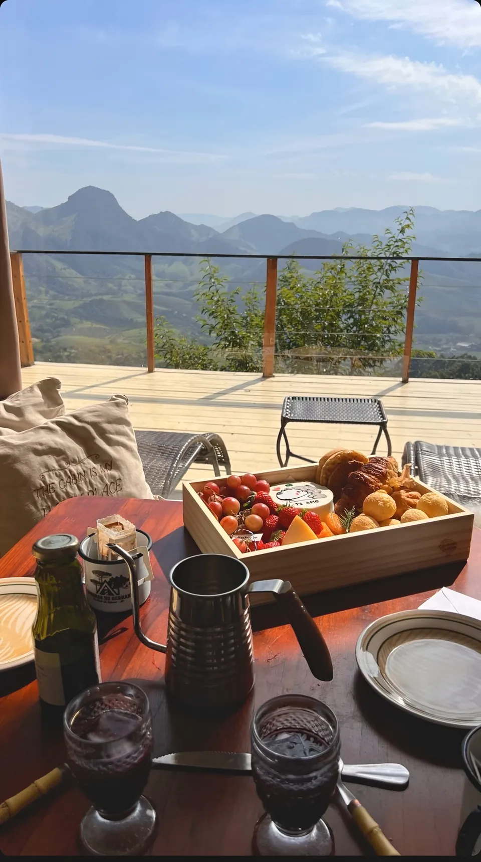 Mesa de café com a cesta, bule e taças, de frente para as montanhas.