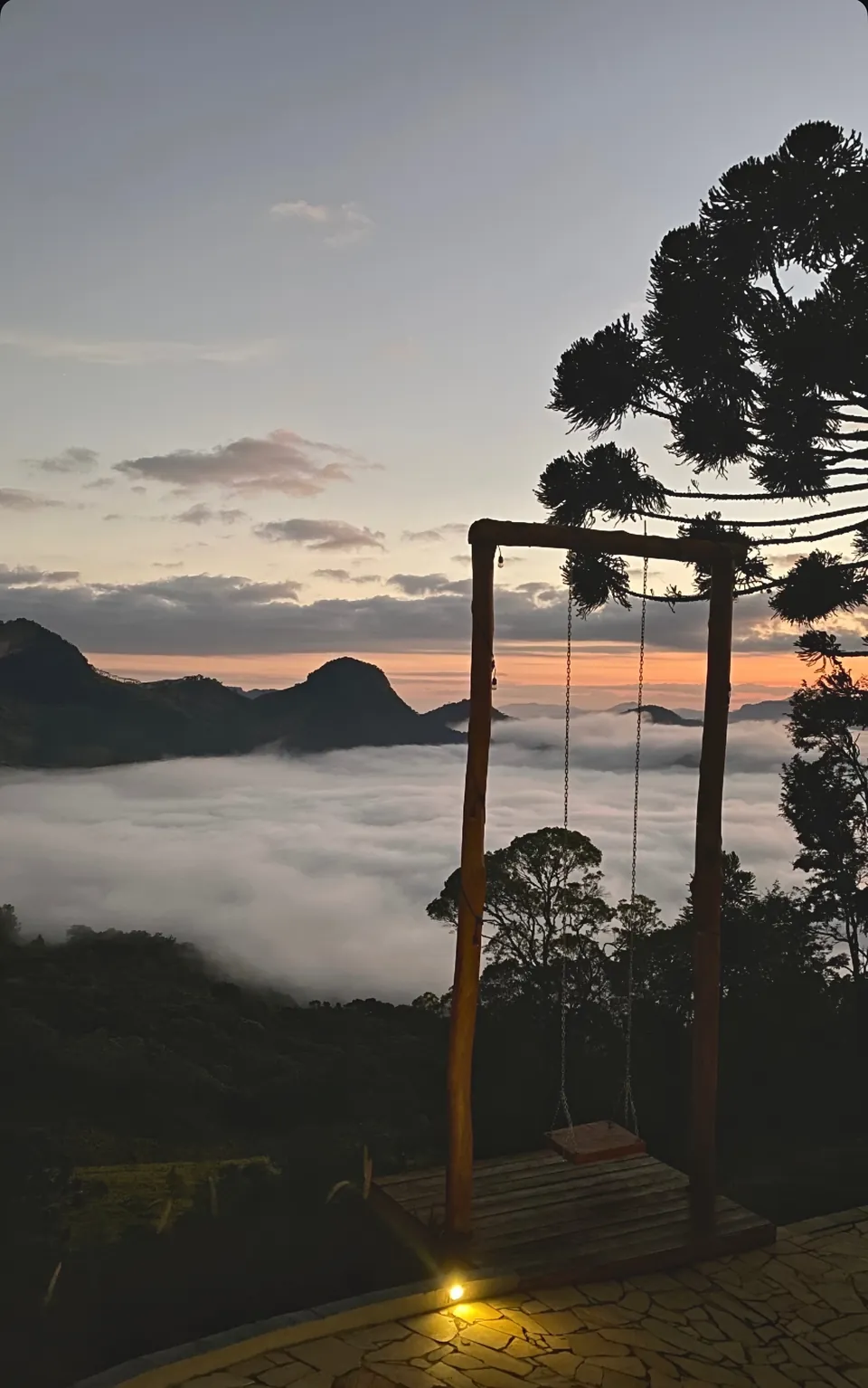 Balanço ao entardecer, com o céu rosado e a névoa cobrindo o vale.