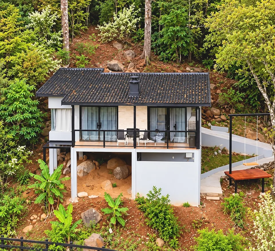 Mantiqueira inteira vista do alto na encosta, com a varanda envidraçada, a chaminé da lareira e o balanço ao lado, entre a mata.